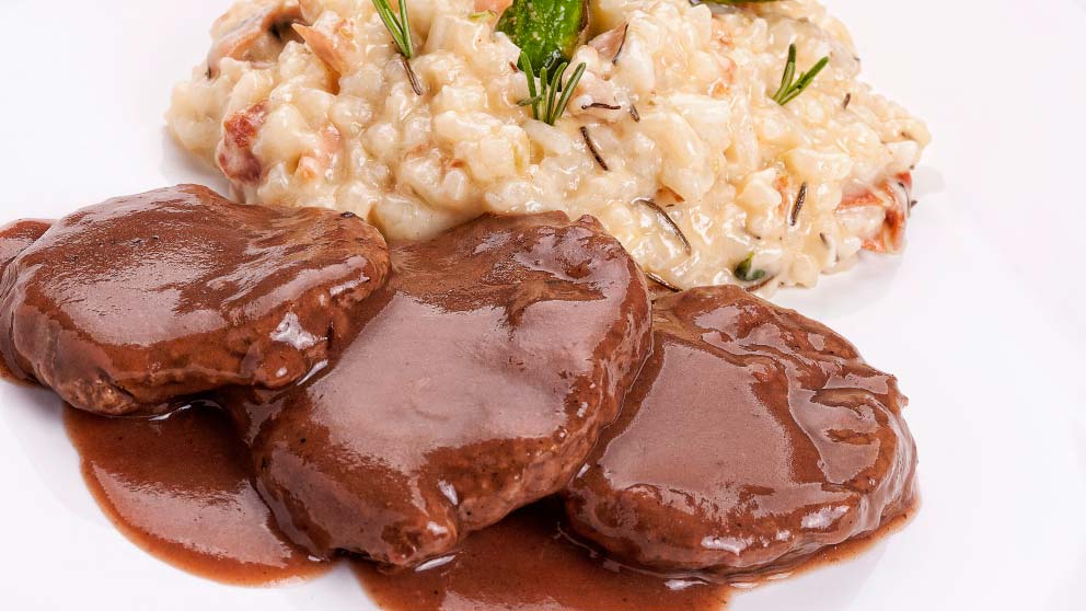 Medallions of secreto ibérico in a brown sauce served with creamy rice and herbs