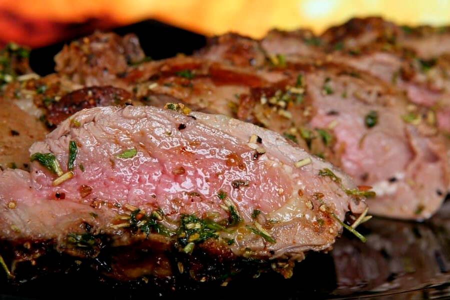 Über Holzkohle gegrillter Secreto Ibérico in Scheiben, innen rosa und mit Kräutern bestreut