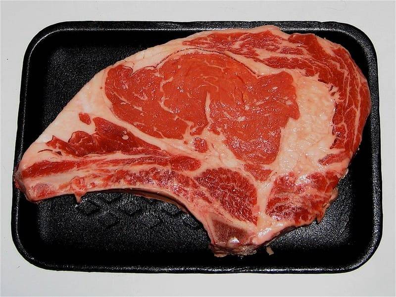 Rohes Chuletón vom Retinto-Jungrind auf einer schwarzen Metzgerschale, von oben gesehen
