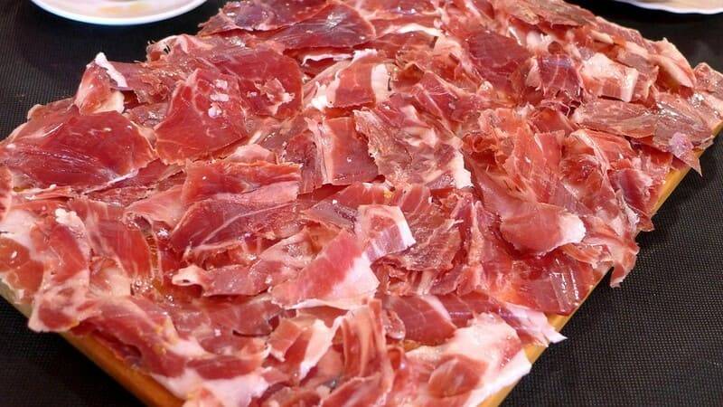 Handgeschnittene Späne vom Ibérico-Bellota-Schinken, auf einem Servierbrett verteilt